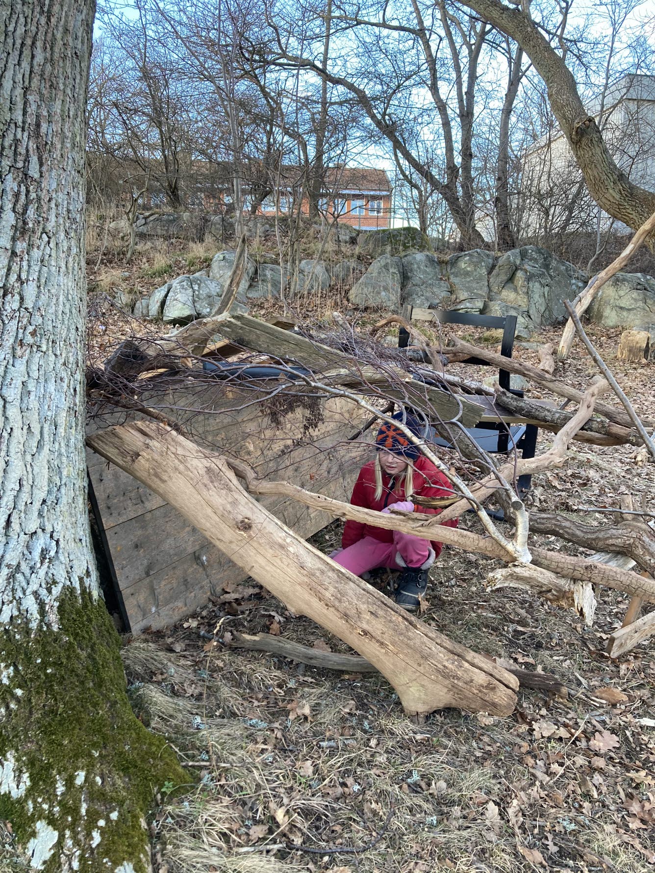 Bild på en flicka som leker i en koja som är byggd av upphittat material.