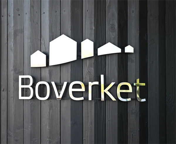 Svart sotad fasad med boverkets logga på.