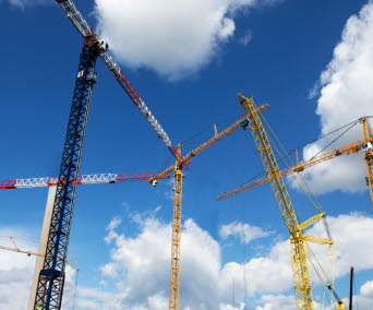 Byggkranar mot en blå himmel med små moln. Foto: Hans Ekestang