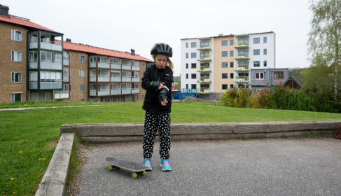 Barn med skateboard på en gård framför flerbostadshus. Foto: Franz Feldmanis