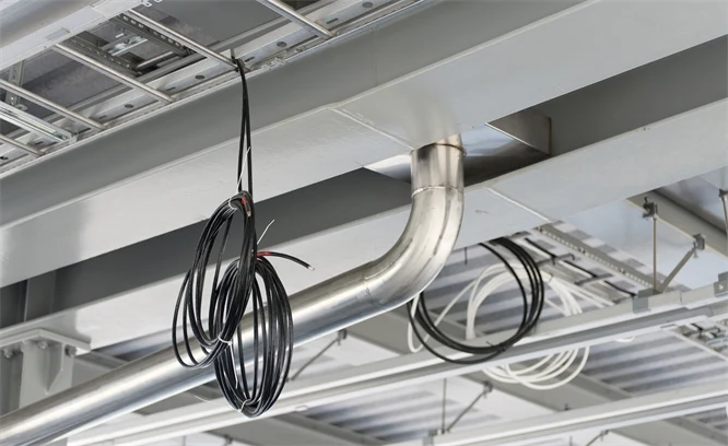 Foto på innertak i fastighet med kablar, rör och ventilation.