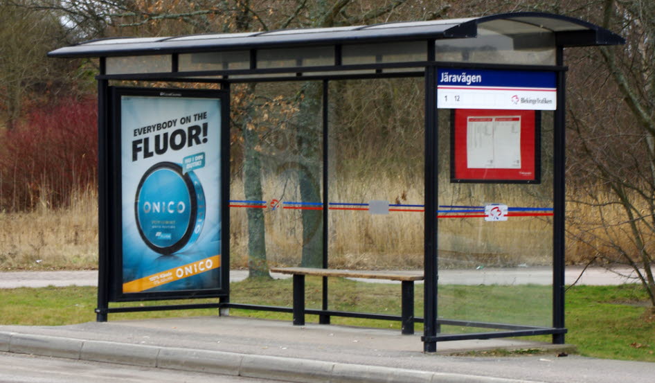 Foto på ett väderskydd på en busshållplats med en reklamtavla på ena gaveln med reklam för snus på tavlan.