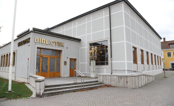 Bibliotek i en grå byggnad med guldbokstäver över entredörren.