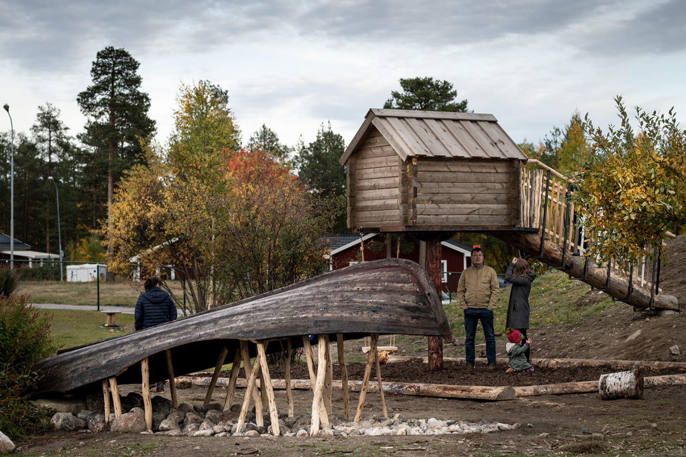 Uppochnervänd båt i trä och en stuga i trä som står på pålar med en landgång som går till den.