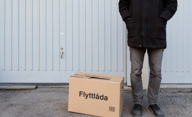 Person som står utanför ett garage, bredvid en flyttkartong.