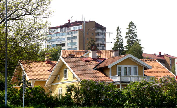 Gul trävilla framför flerbostadshus. Foto: Hans Ekestang.