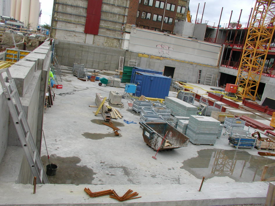 Byggarbetsplats med vatten på exponerad betongplatta.