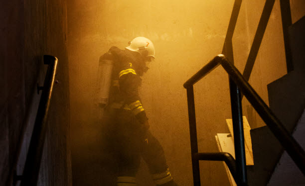 Foto på brandman i ett rökfyllt trapphus.