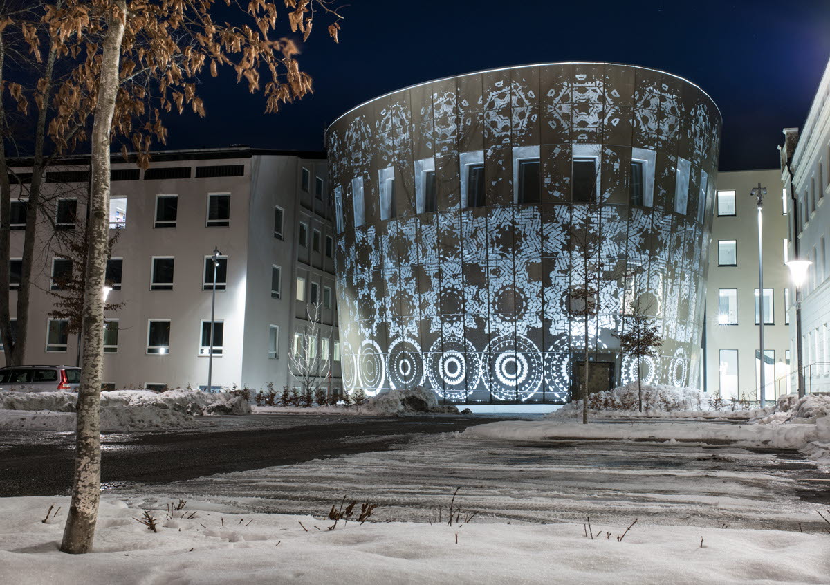 Fasaden på Humanistiska teatern i Uppsala där dess runda form belyses av olika mönster som ett konstverk.