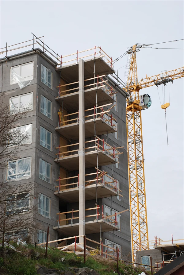 Bild på ett bygge av ett flerbostadshus med intilliggande lyftkran.