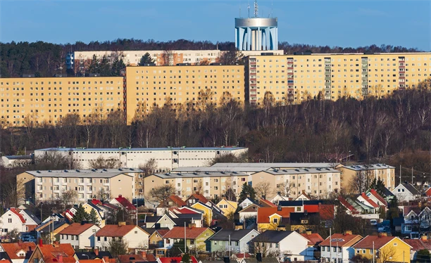 Stadsbild med flerfamiljshus, vattentorn och villor.