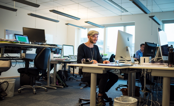 En kille sitter vid ett skrivbord och jobbar med dator.