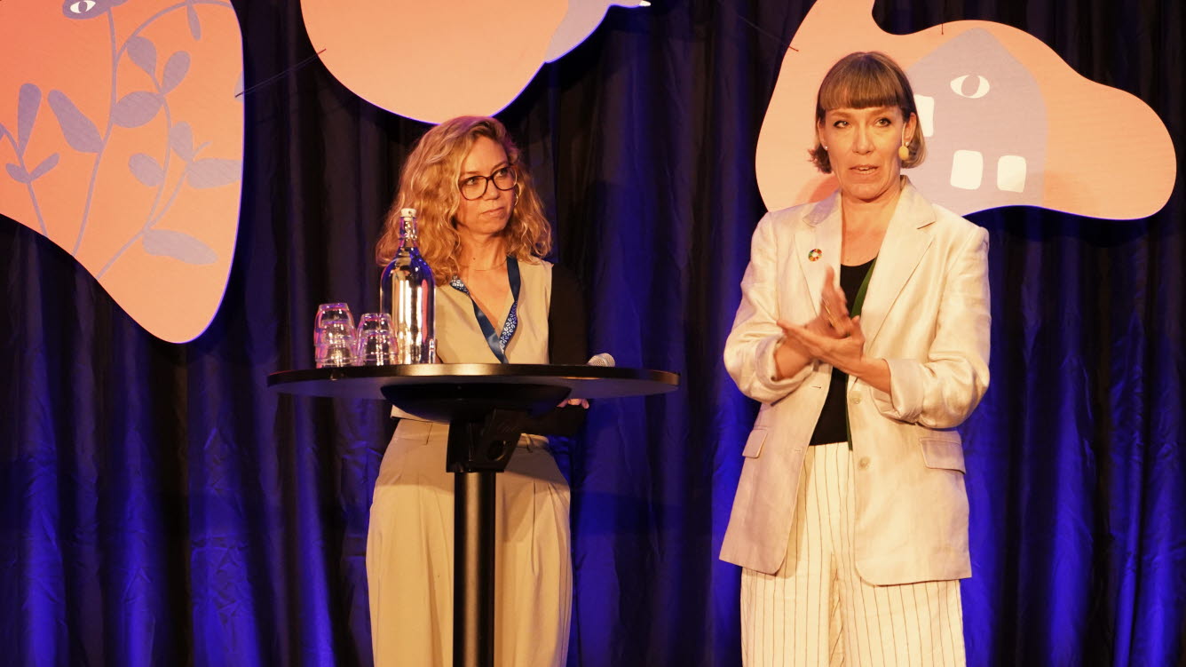 Foto av två kvinnor i ett samtal på konferensens scen. 