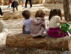 Barn som sitter på en stock på en förskolegård.