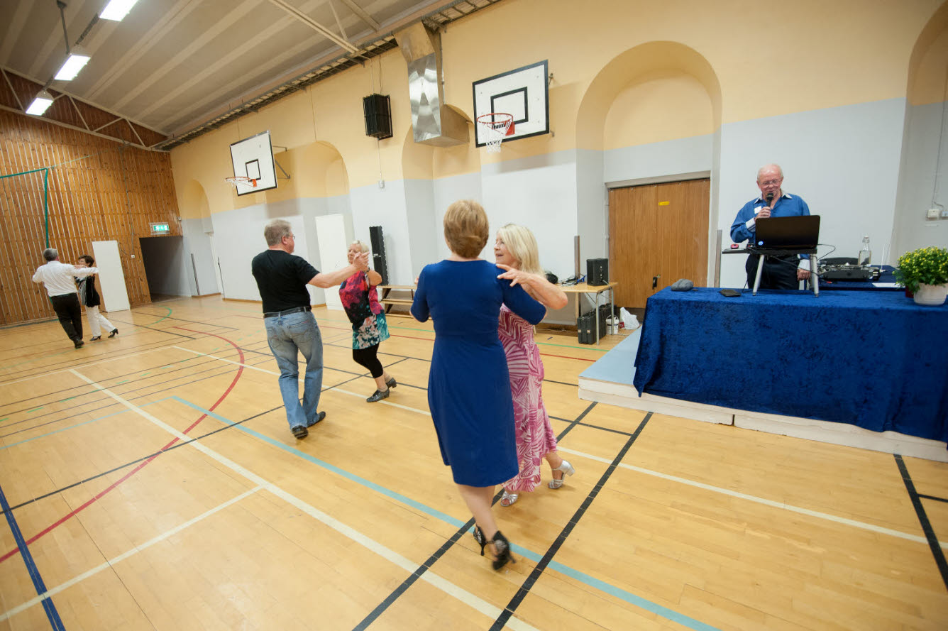 Foto på personer som dansar i en gymnastiksal.
