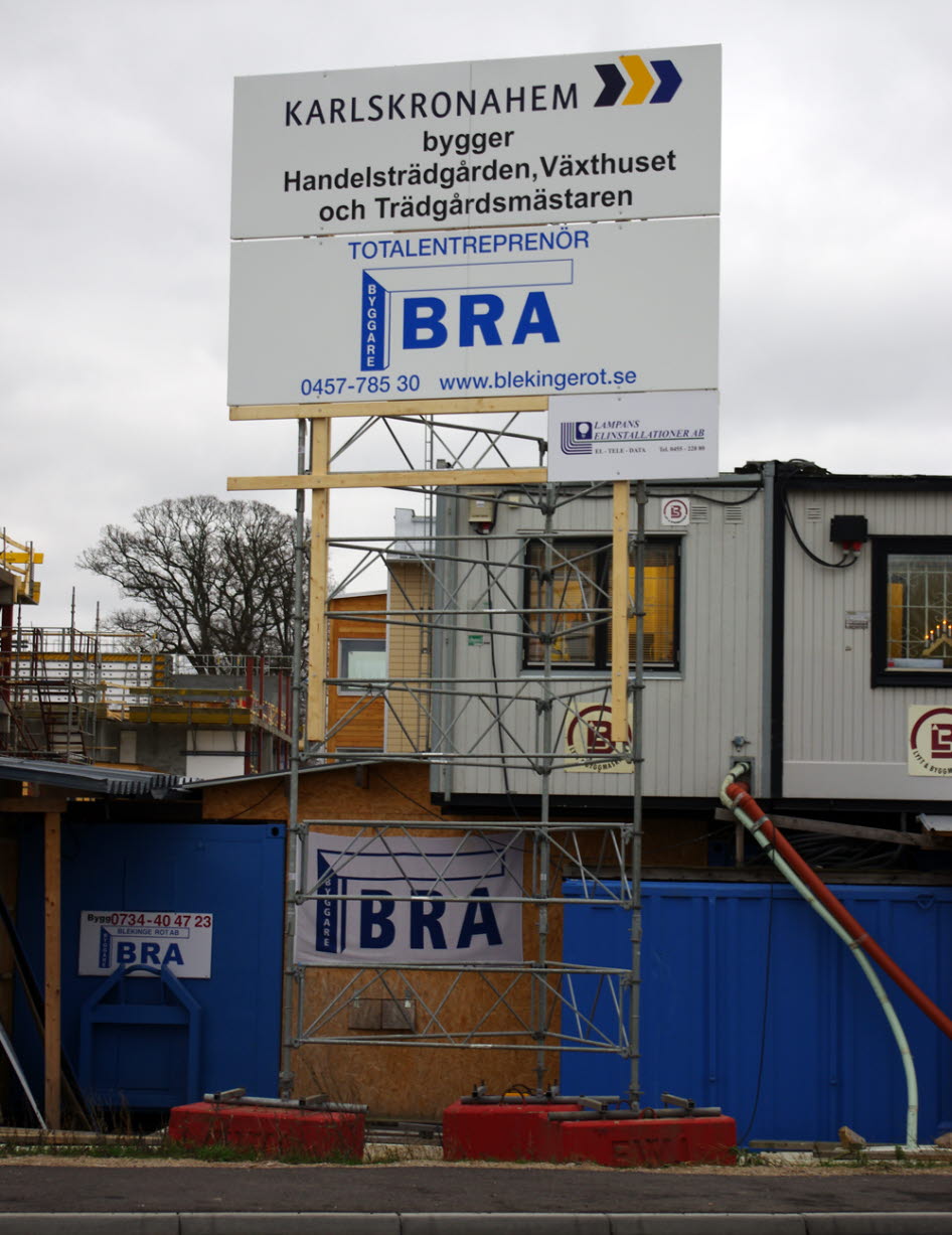 Foto på en skylt vid en byggarbetsplats med reklam för byggherren och entrepenörer.
