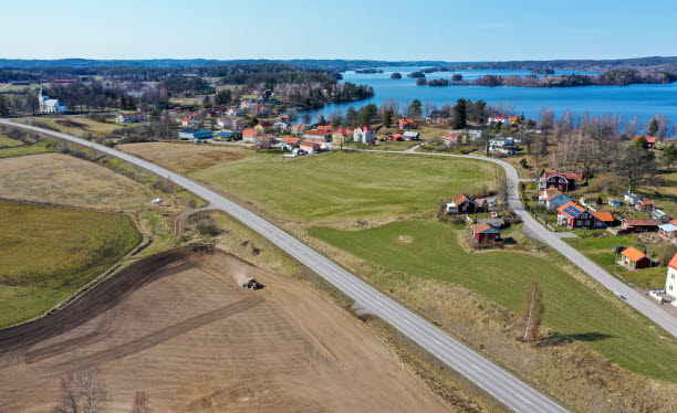 Flygfoto som visar åkrar, landsvägar och bebyggelse framför havet.