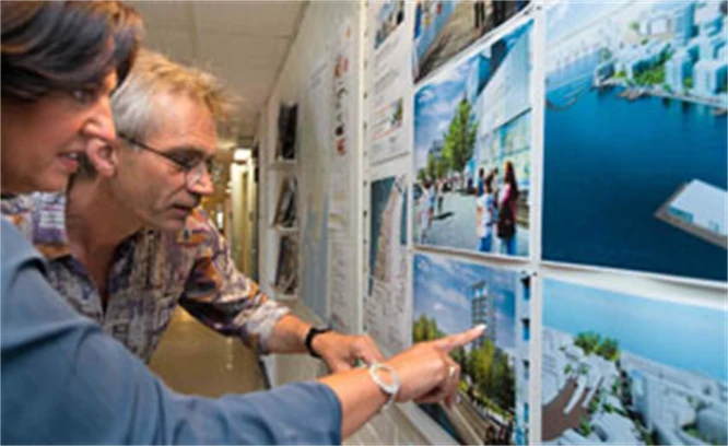 Två personer pekar på arkitektskisser. Foto: Franz Feldmanis
