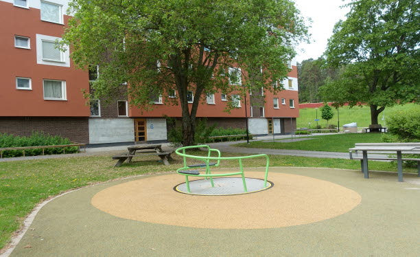 Buskar, träd och utemöbler på en innergård vid ett flerbostadshus. Foto: Ida Jonskog/Boverket.