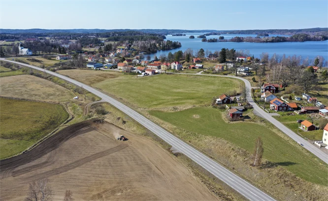 Flygfoto som visar åkrar, landsvägar och bebyggelse framför havet.