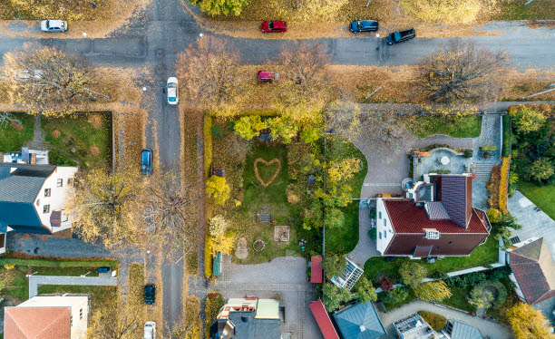 Flygfoto som visar en fyrvägskorsning, grönytor och hus.