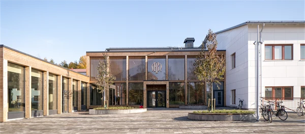 Exteriör bild på skolans tillbyggda entré vid en stenlagd yta.