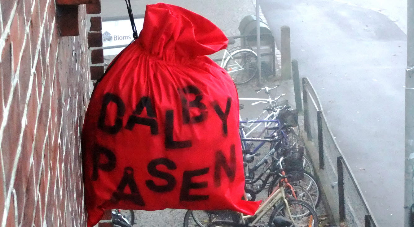 En röd säck som hänger i ett snöre ovanför ett cykelställ. Foto: Annika André