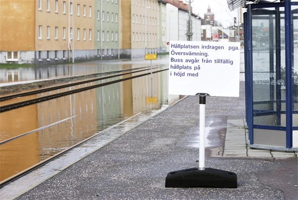 Foto på indragen busshållplats på översvämmad gata.