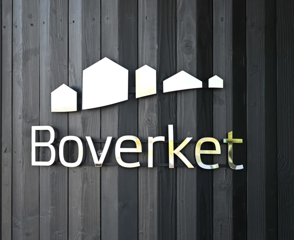 Svart sotad fasad med boverkets logga på.