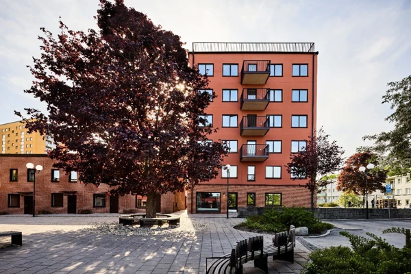 Flerbostadshus med träd och buskar framför.