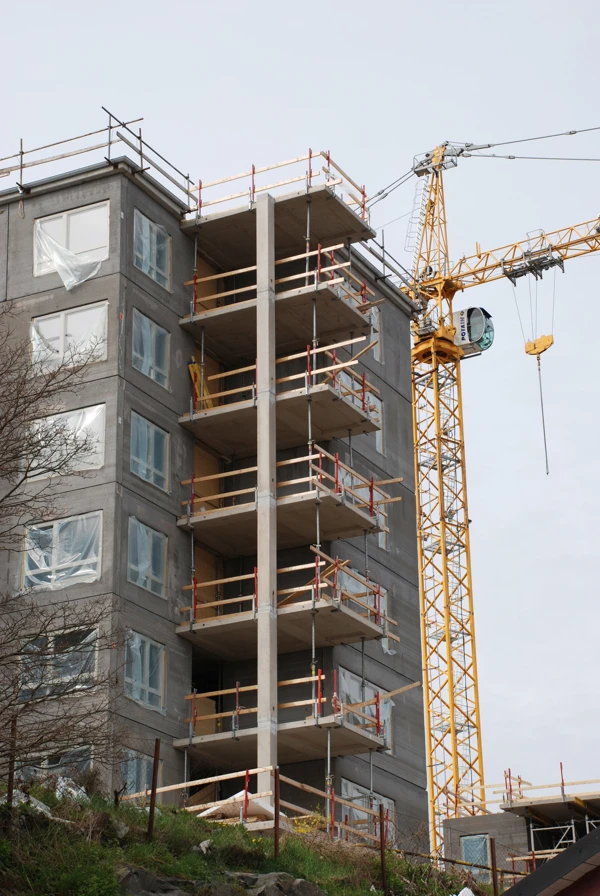 Bild på ett bygge av ett flerbostadshus med intilliggande lyftkran.