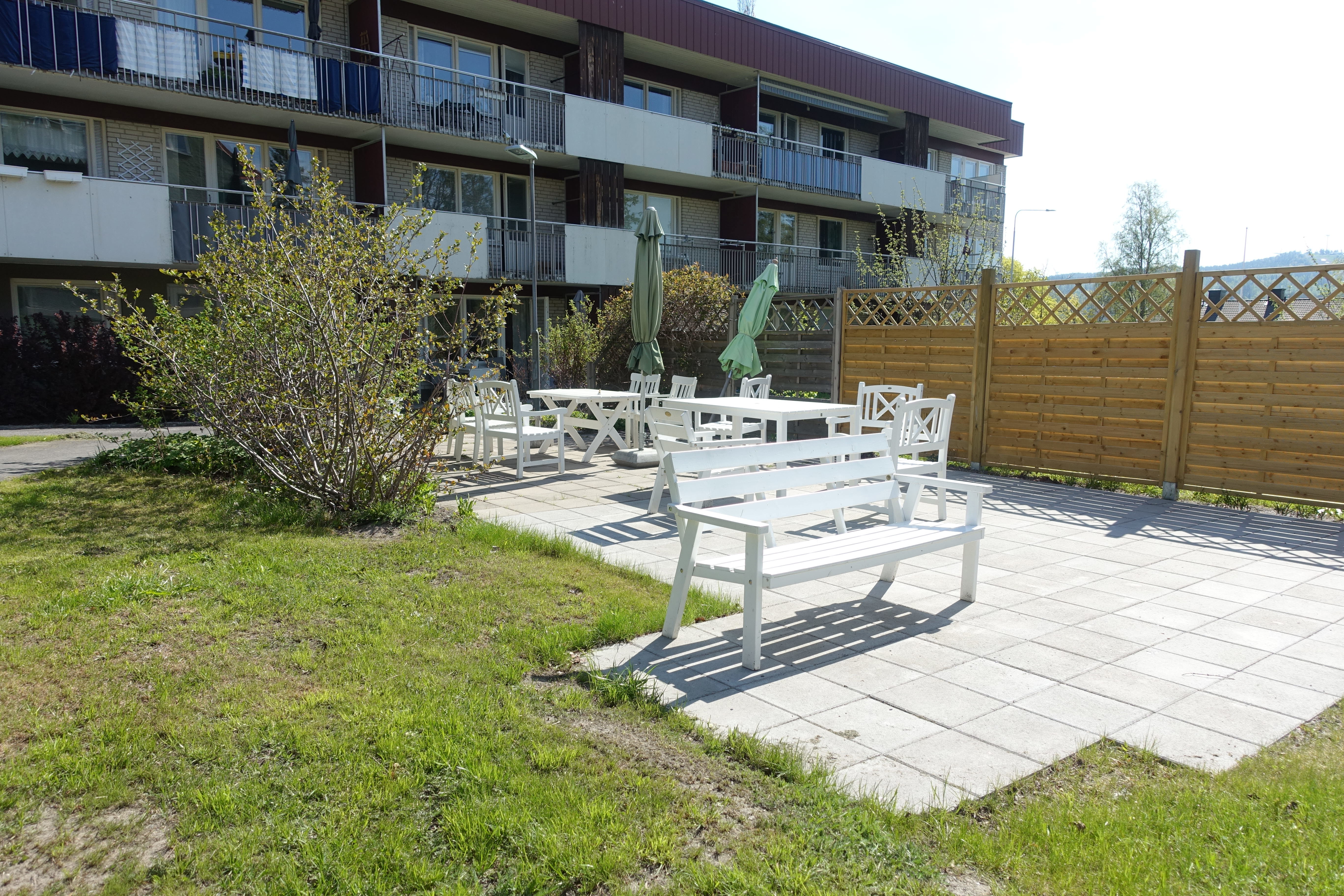 Innergård med gräsmatta, buskar och trädgårdsmöbler vid flerbostadshus. Foto: Ida Jonskog/Boverket.
