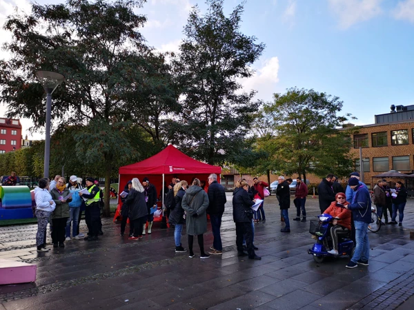 Människor som möts och pratar på ett torg.