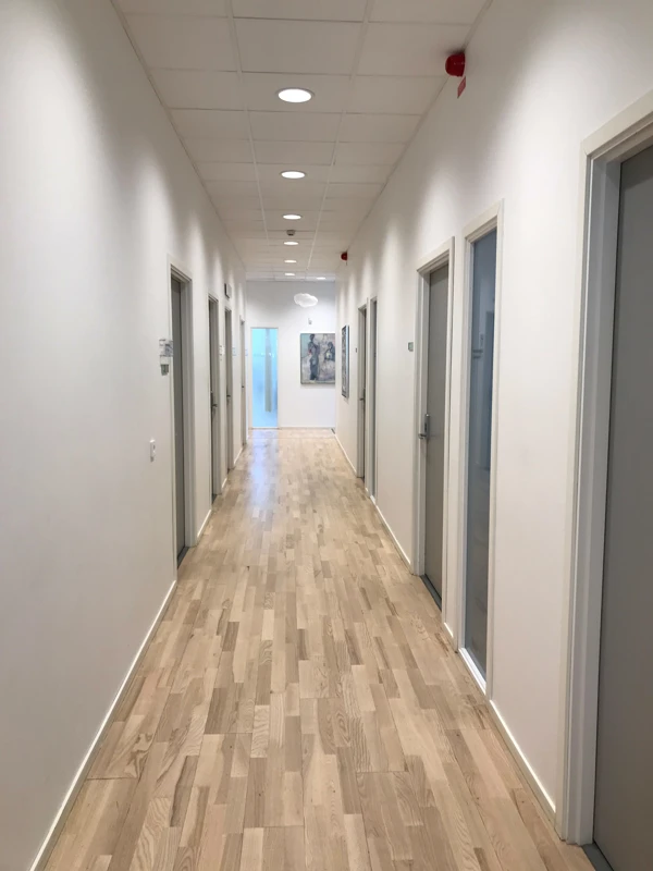 Foto på vårdcentralens vita korridor med tavlor.