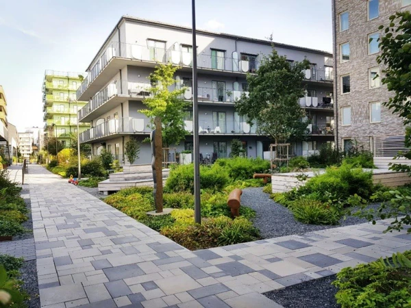 Stenlagda gångar som löper genom kvarteret mellan de moderna bostadshusen. Mellan husen finns olika grönytor.