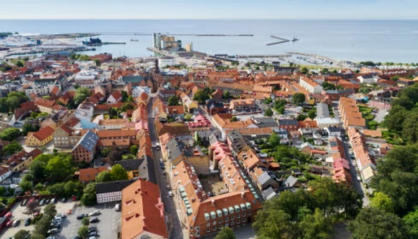 Flygfoto över stad med bostäder, lokaler industri och hamn med mera