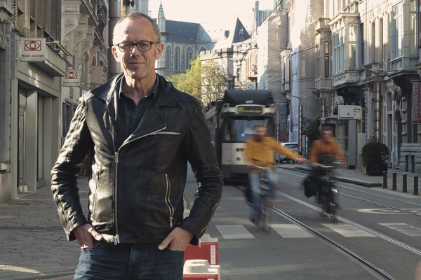 Porträttbild av Filip Watteeuw, biträdande borgmästare i Gent. I bakgrunden finns cyklister och buss.
