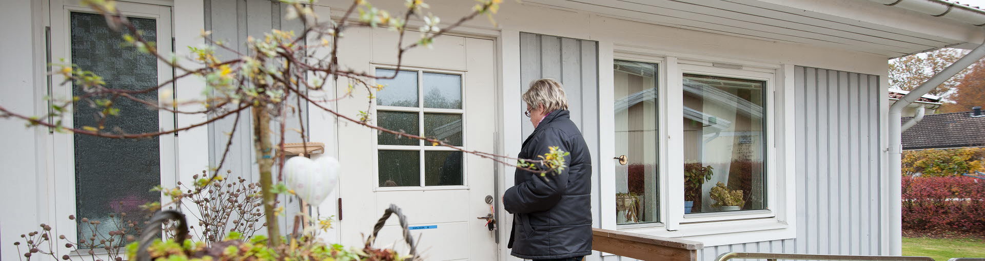 En kvinna sätter nyckeln i dörren på en villa.