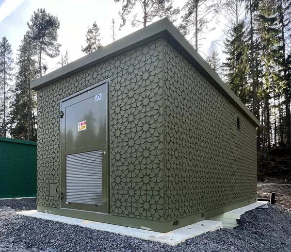 Foto av station med platt tak och blom-mönstrat fasadmaterial i mossgröna nyanser.