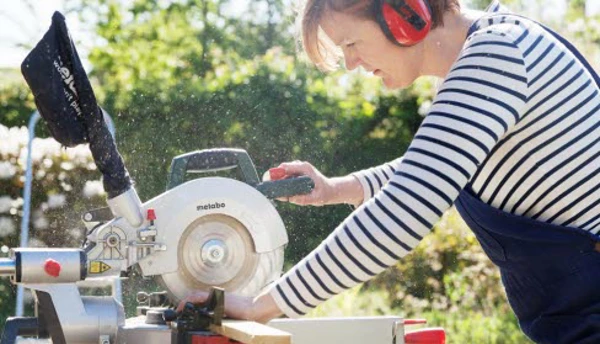 En kvinna som kapar en bräda med en elektrisk såg.