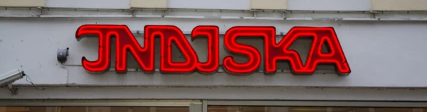 Foto på neonskylt med texten Indiska på en fasad.