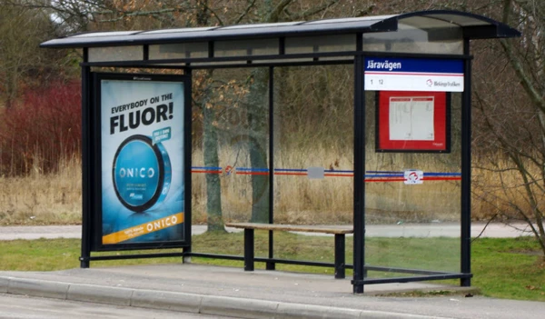 Foto på ett väderskydd på en busshållplats med en reklamtavla på ena gaveln med reklam för snus på tavlan.