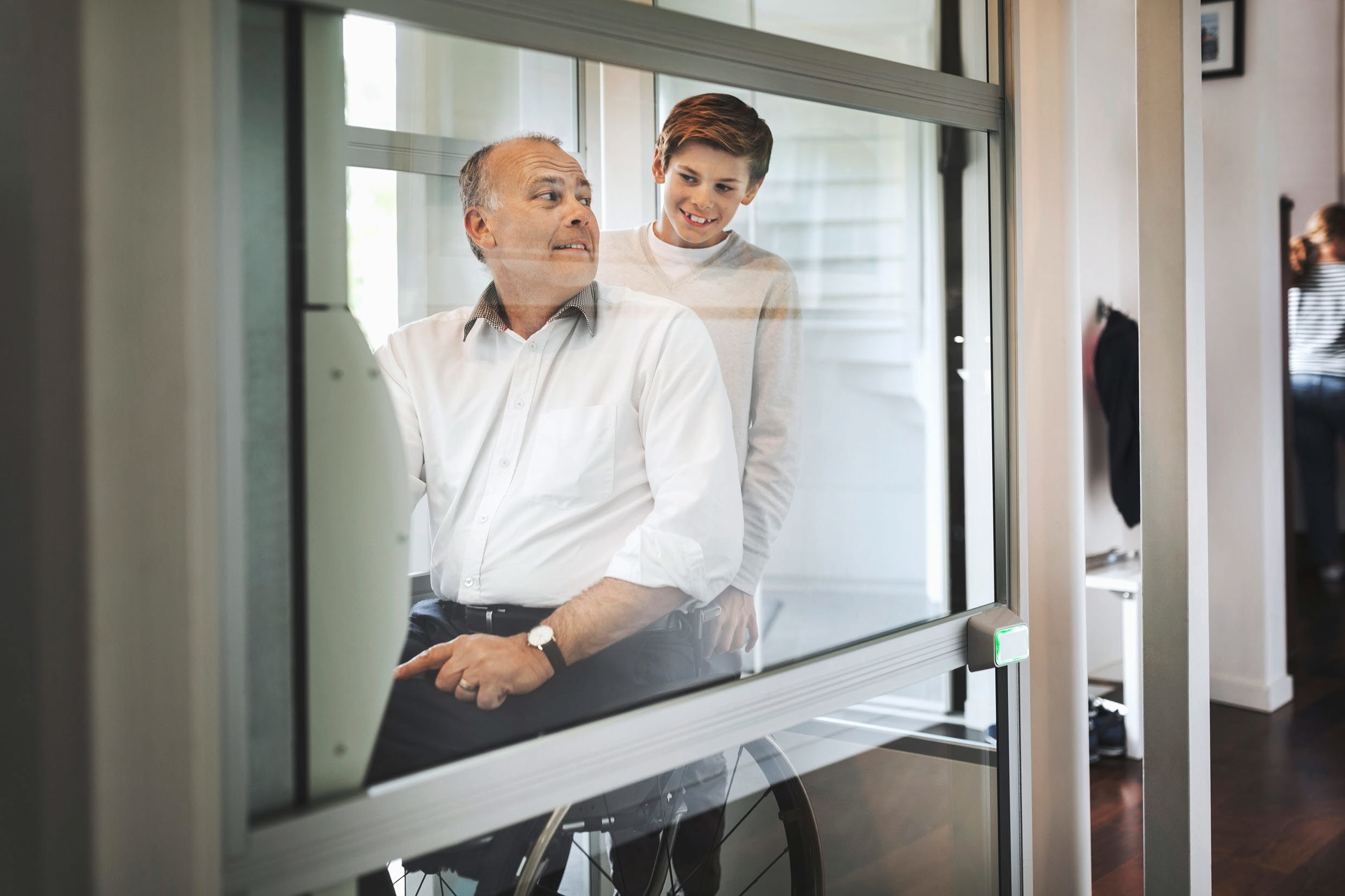 Far i rullstol och son åker hiss i  bostad. Foto: Maskot Bildbyrå AB/Johnér Bildbyrå.